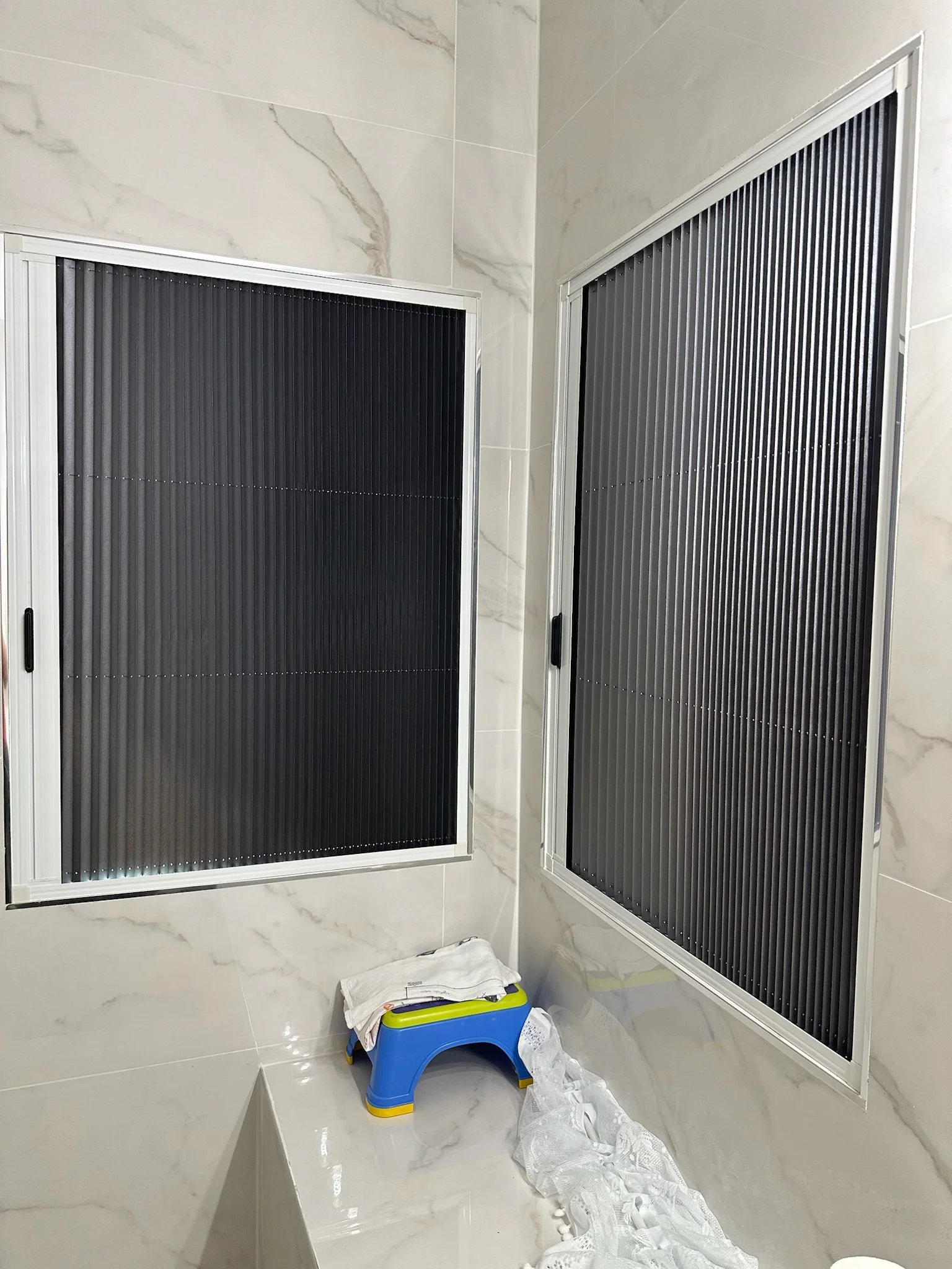 Pleated window screens fitted to two adjacent windows