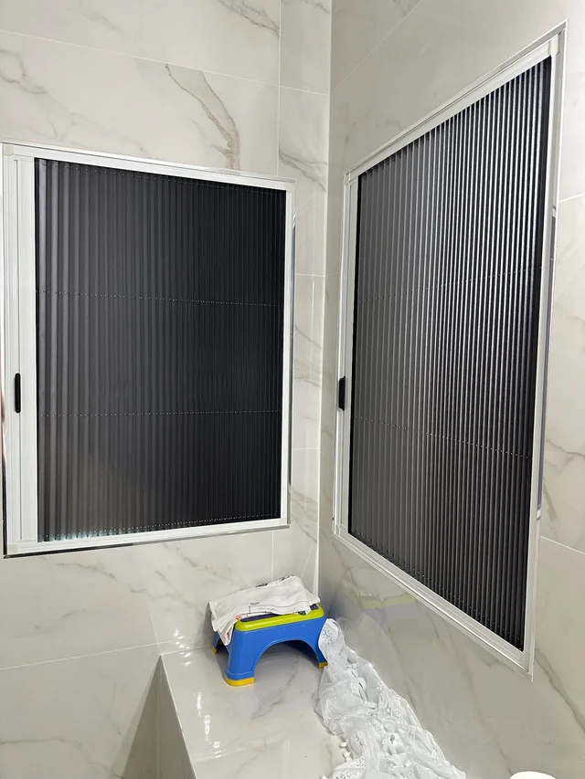 Pleated window screens fitted to two adjacent windows